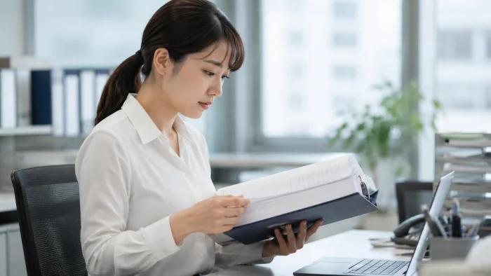 就業規則の資料を集中して読み込む日本人女性人事担当者