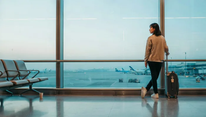 空港の窓から駐機する航空機を眺めるビジネスパーソン